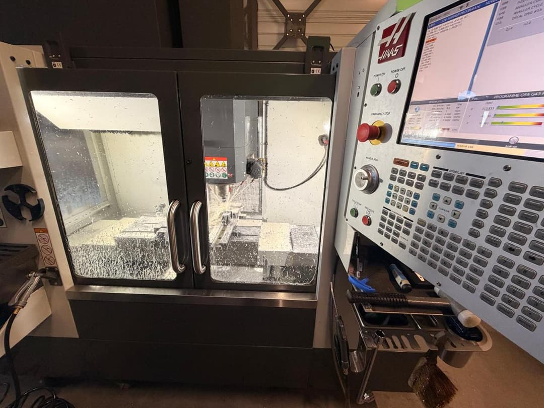 Fraiseuse Haas CNC en plein usinage d'aluminium avec précision, visible dans un atelier industriel moderne.